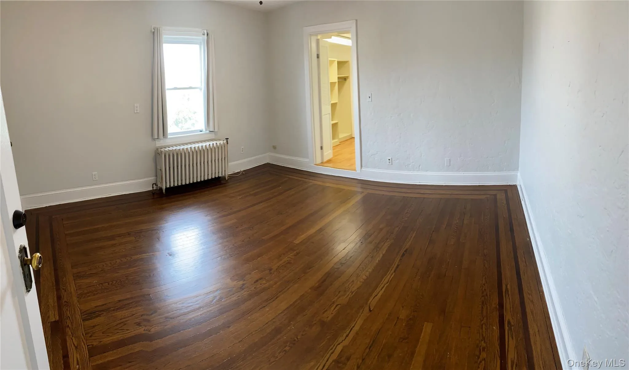Unfurnished room with radiator and wood finished floors Unfurnished room with radiator and wood finished floors