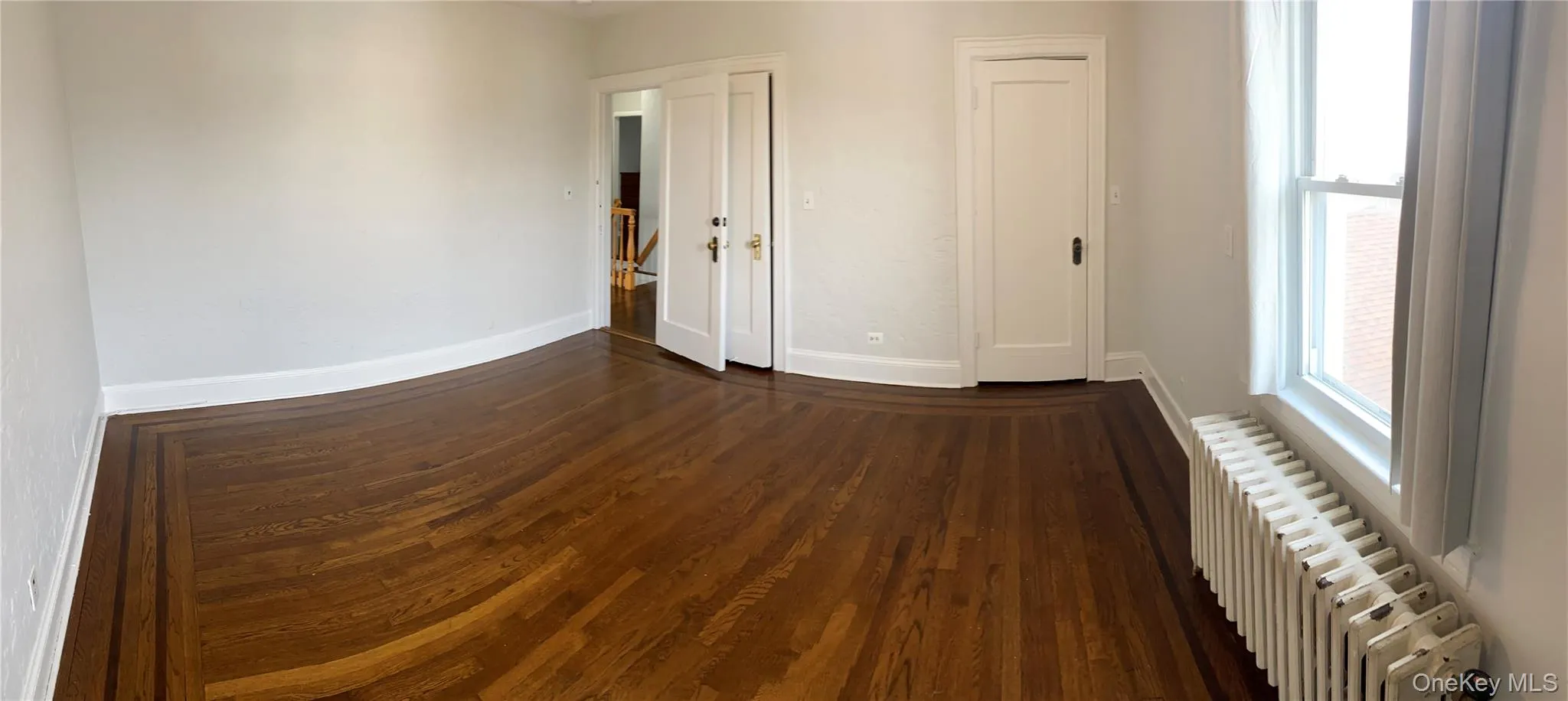 Spare room featuring radiator and dark wood finished floors Spare room featuring radiator and dark wood finished floors