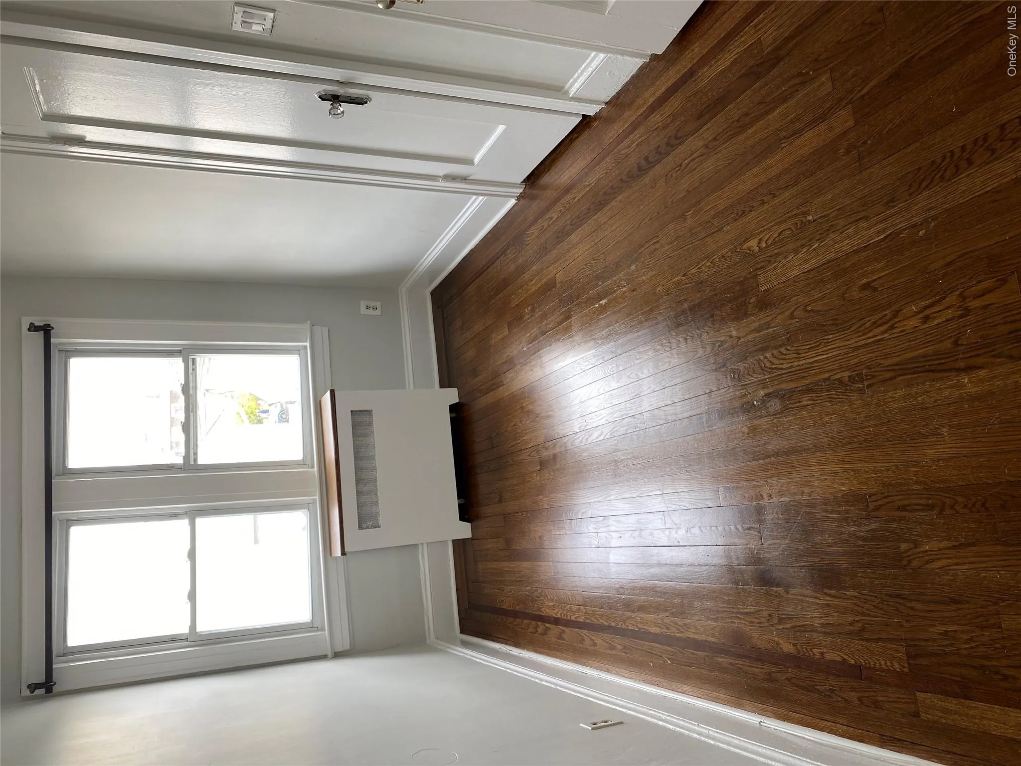 Spare room featuring radiator heating unit and dark wood-style flooring Spare room featuring radiator heating unit and dark wood-style flooring
