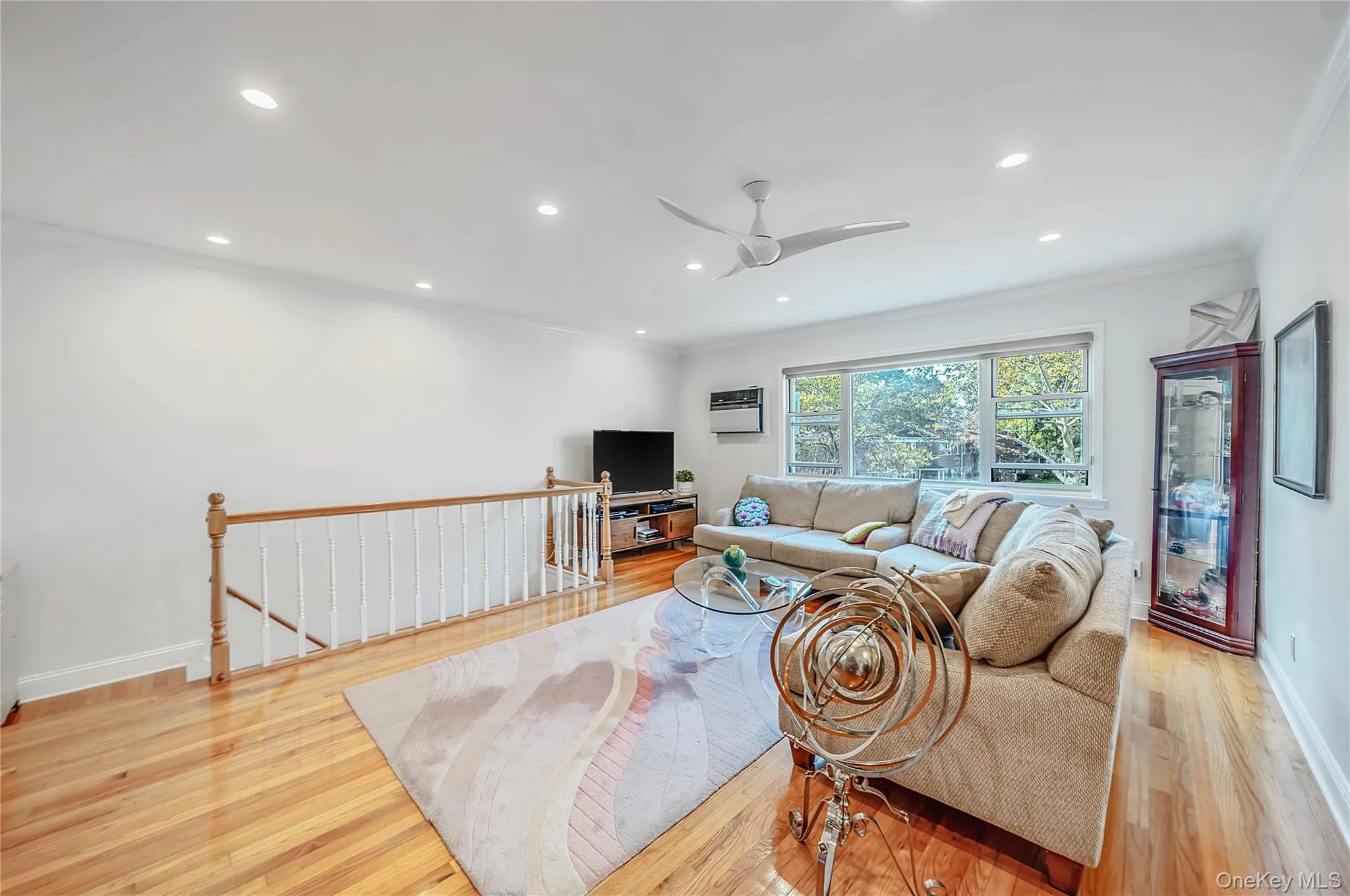 Living space featuring wood-finish flooring, recessed lighting, a ceiling fan, and a wood-railing staircase Living space featuring wood-finish flooring, recessed lighting, a ceiling fan, and a wood-railing staircase
