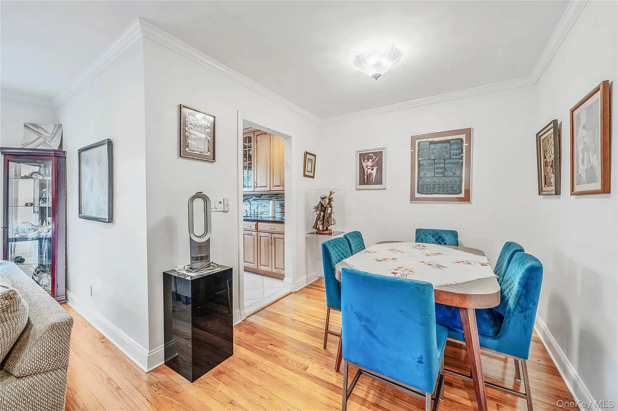 Dining space featuring wood-finish flooring, crown molding, and a flush-mount light fixture Dining space featuring wood-finish flooring, crown molding, and a flush-mount light fixture