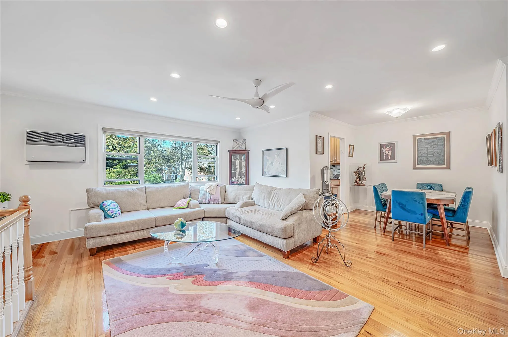 Open-concept living space featuring wood-finish flooring, recessed lighting, crown molding, and large windows Open-concept living space featuring wood-finish flooring, recessed lighting, crown molding, and large windows