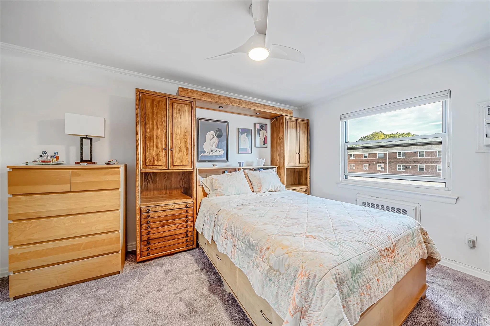 Custom built-in wooden cabinetry with integrated storage and overhead lighting, ceiling fan with light fixture, and large dual-pane window Custom built-in wooden cabinetry with integrated storage and overhead lighting, ceiling fan with light fixture, and large dual-pane window