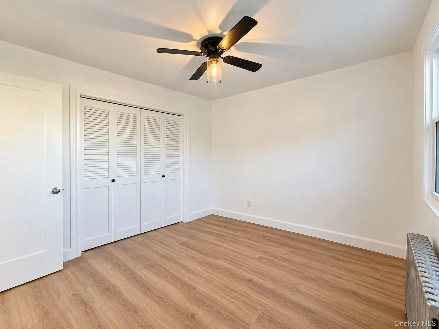 Wood-finish flooring, multi-panel louvered closet doors, and a ceiling fan with integrated lighting Wood-finish flooring, multi-panel louvered closet doors, and a ceiling fan with integrated lighting
