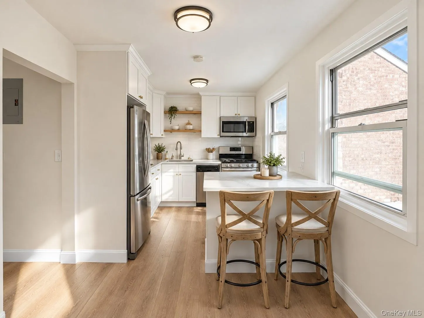 Kitchen featuring white cabinetry, stainless steel appliances, stone-finish countertops, wood-finish flooring, and floating wood shelving Kitchen featuring white cabinetry, stainless steel appliances, stone-finish countertops, wood-finish flooring, and floating wood shelving