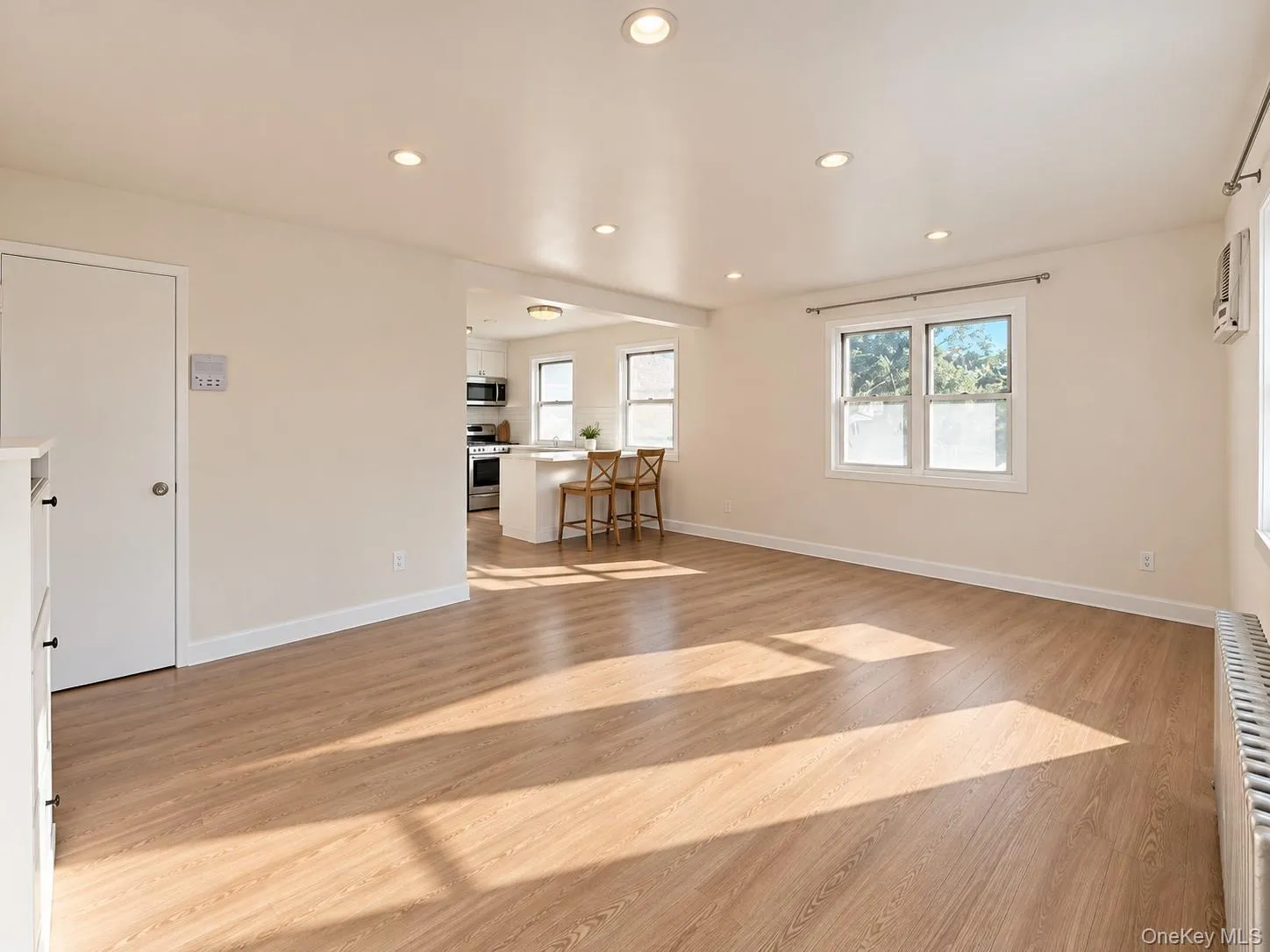 Interior space featuring wood-finish flooring, recessed lighting, double-hung windows, and a breakfast bar Interior space featuring wood-finish flooring, recessed lighting, double-hung windows, and a breakfast bar