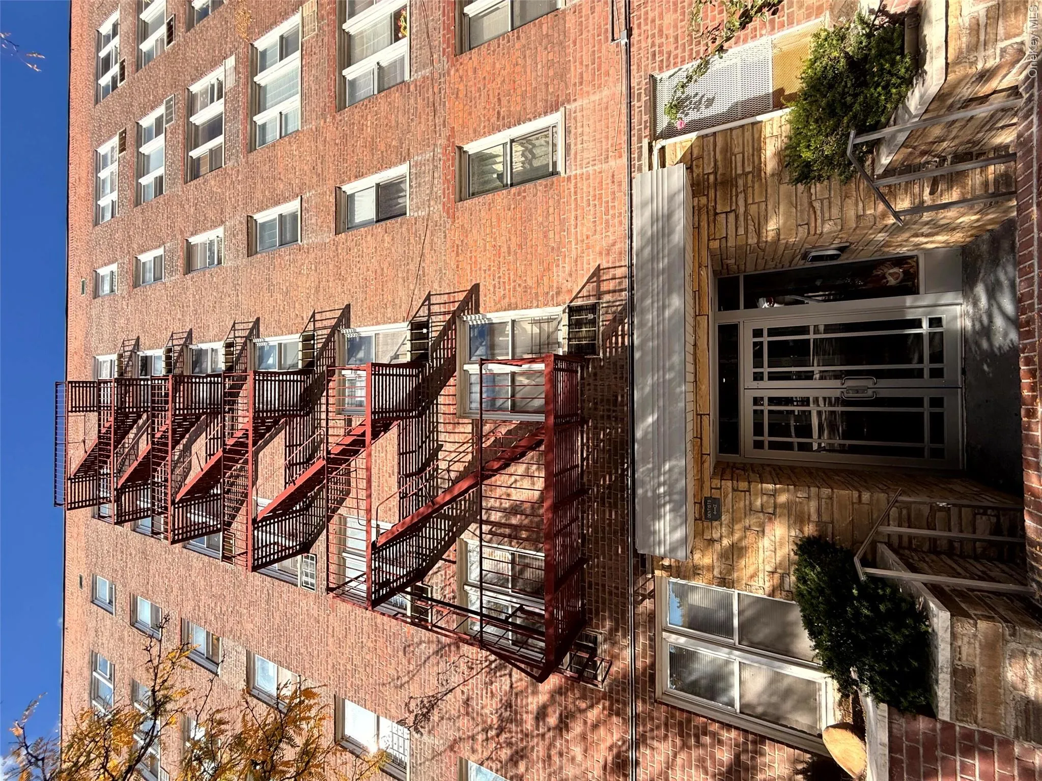 Classic red brick exterior featuring a multi-story metal fire escape, stone masonry facade at the entrance, and double-glass entry doors Classic red brick exterior featuring a multi-story metal fire escape, stone masonry facade at the entrance, and double-glass entry doors