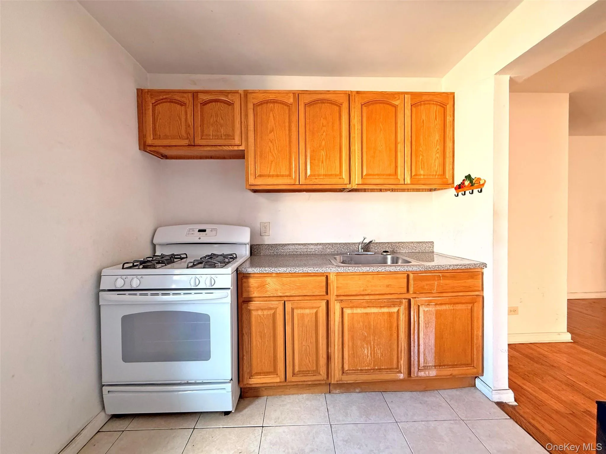 Kitchen featuring wood cabinetry, solid-surface countertops, integrated stainless steel sink, and gas range Kitchen featuring wood cabinetry, solid-surface countertops, integrated stainless steel sink, and gas range