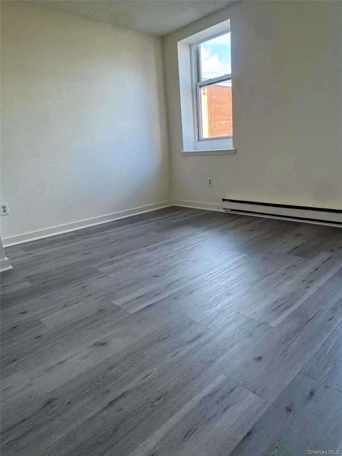 Spare room with dark wood-type flooring, baseboard heating, and a textured ceiling Spare room with dark wood-type flooring, baseboard heating, and a textured ceiling