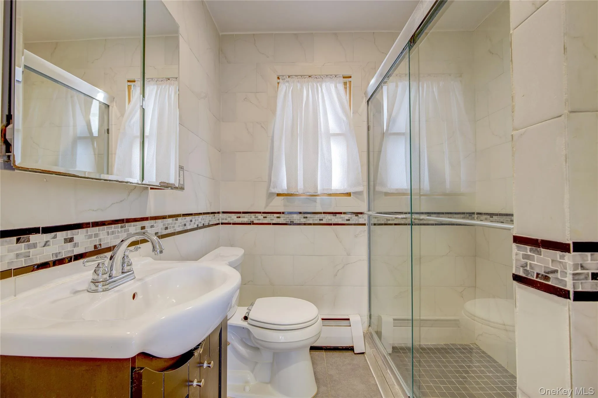 Full bathroom with vanity, toilet, a stall shower, and a baseboard radiator Full bathroom with vanity, toilet, a stall shower, and a baseboard radiator