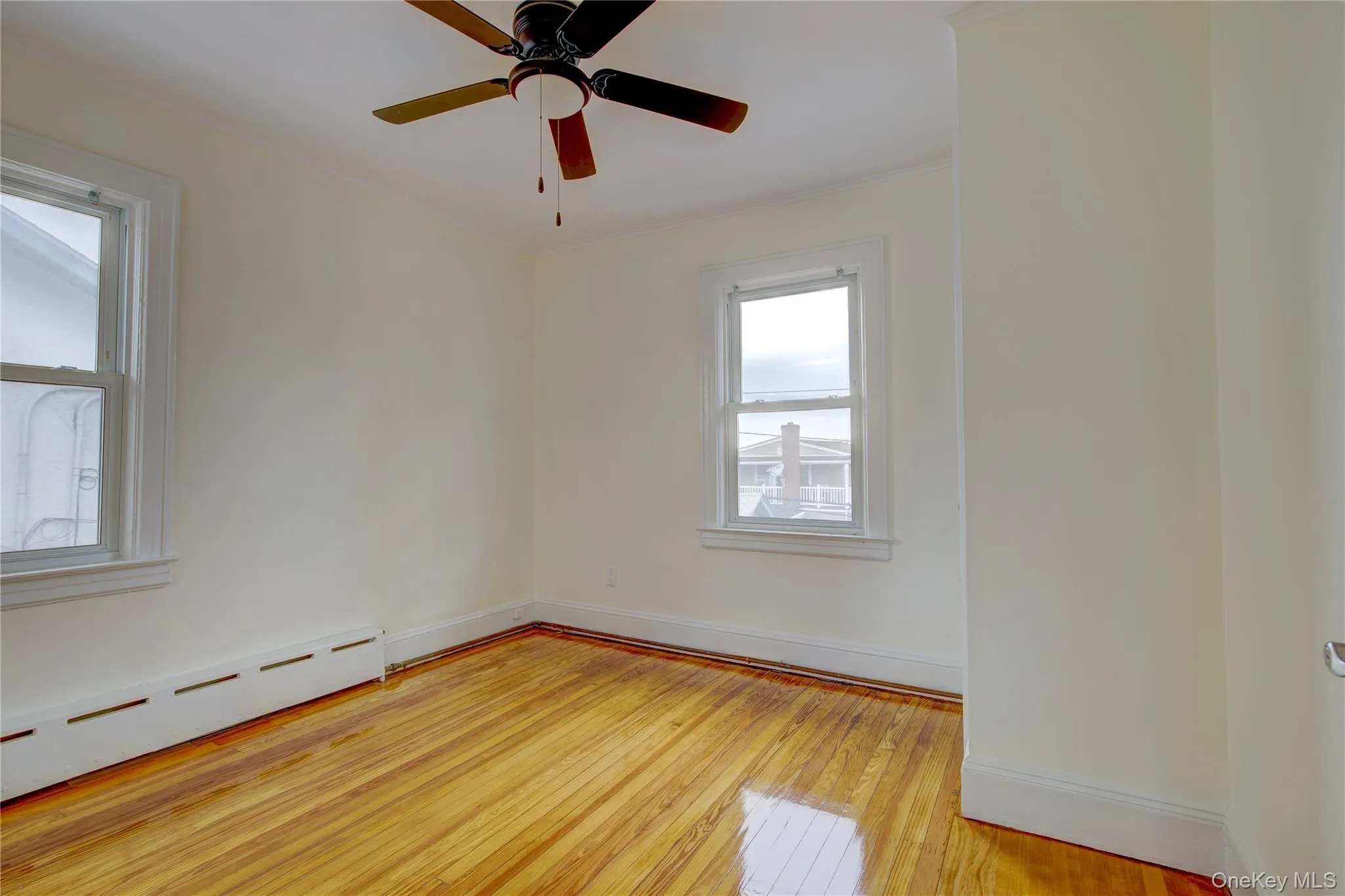 Empty room featuring a baseboard heating unit, baseboards, light wood-style floors, and a ceiling fan Empty room featuring a baseboard heating unit, baseboards, light wood-style floors, and a ceiling fan