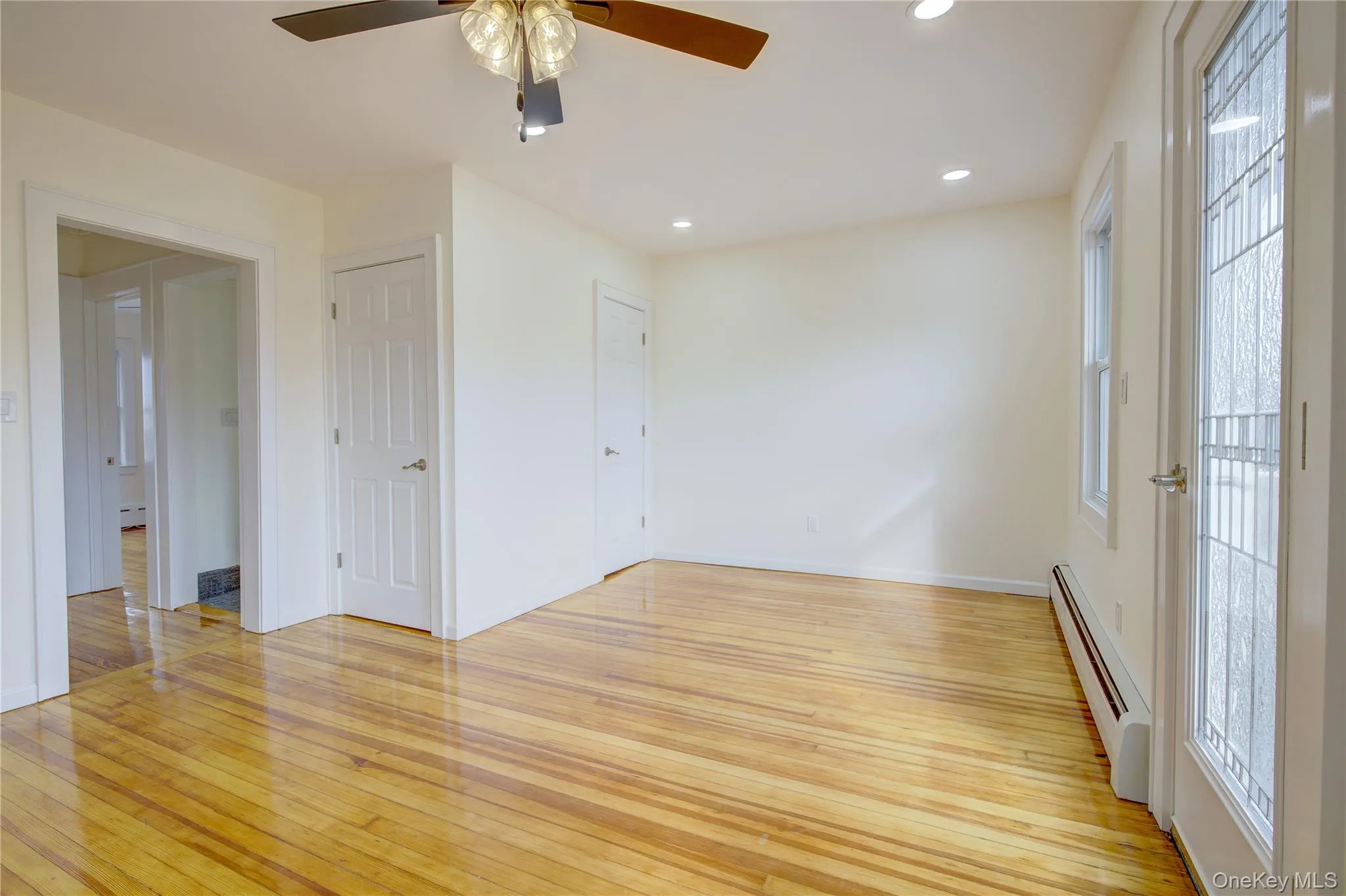 Unfurnished room with hardwood / wood-style flooring, recessed lighting, baseboard heating, and a healthy amount of sunlight Unfurnished room with hardwood / wood-style flooring, recessed lighting, baseboard heating, and a healthy amount of sunlight