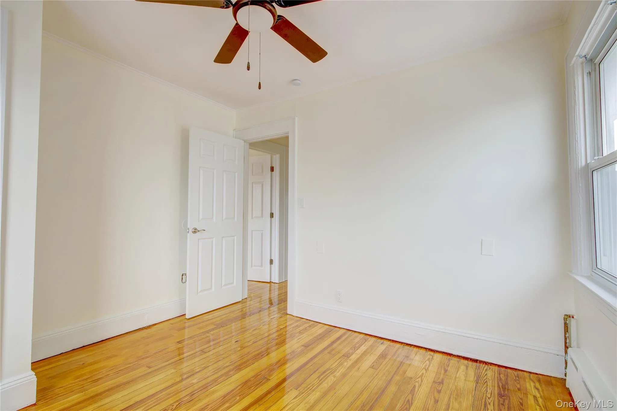 Spare room with light wood-style flooring, baseboards, and ornamental molding Spare room with light wood-style flooring, baseboards, and ornamental molding