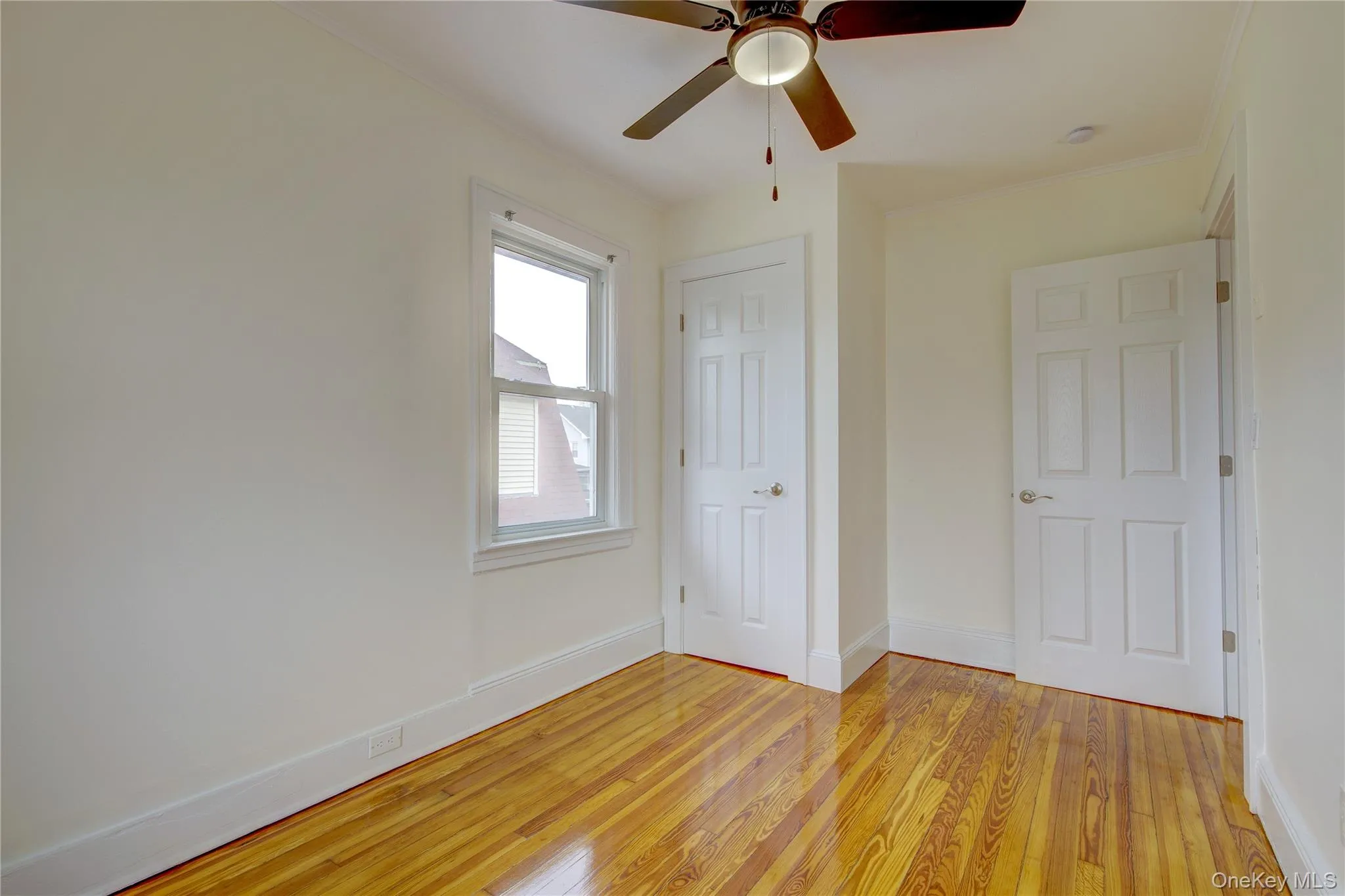 Unfurnished bedroom featuring crown molding, a ceiling fan, light wood-type flooring, and baseboards Unfurnished bedroom featuring crown molding, a ceiling fan, light wood-type flooring, and baseboards