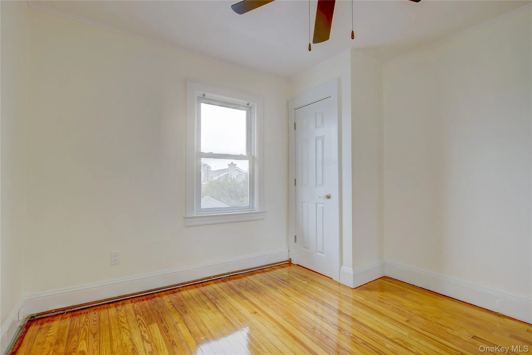 Spare room featuring ceiling fan, light wood-style floors, baseboards, and ornamental molding Spare room featuring ceiling fan, light wood-style floors, baseboards, and ornamental molding