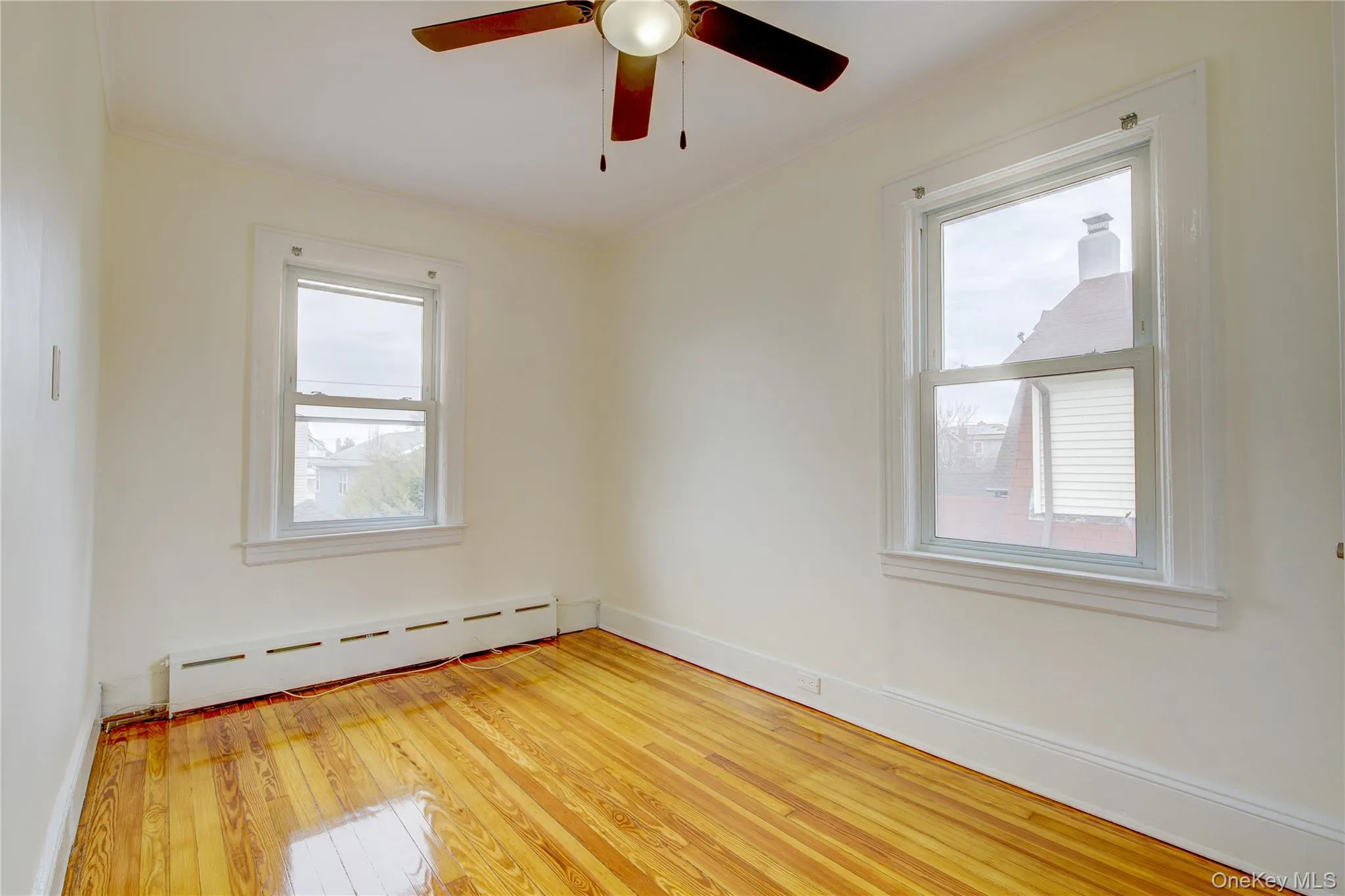 Unfurnished room with light wood-type flooring, a ceiling fan, a baseboard heating unit, crown molding, and baseboards Unfurnished room with light wood-type flooring, a ceiling fan, a baseboard heating unit, crown molding, and baseboards