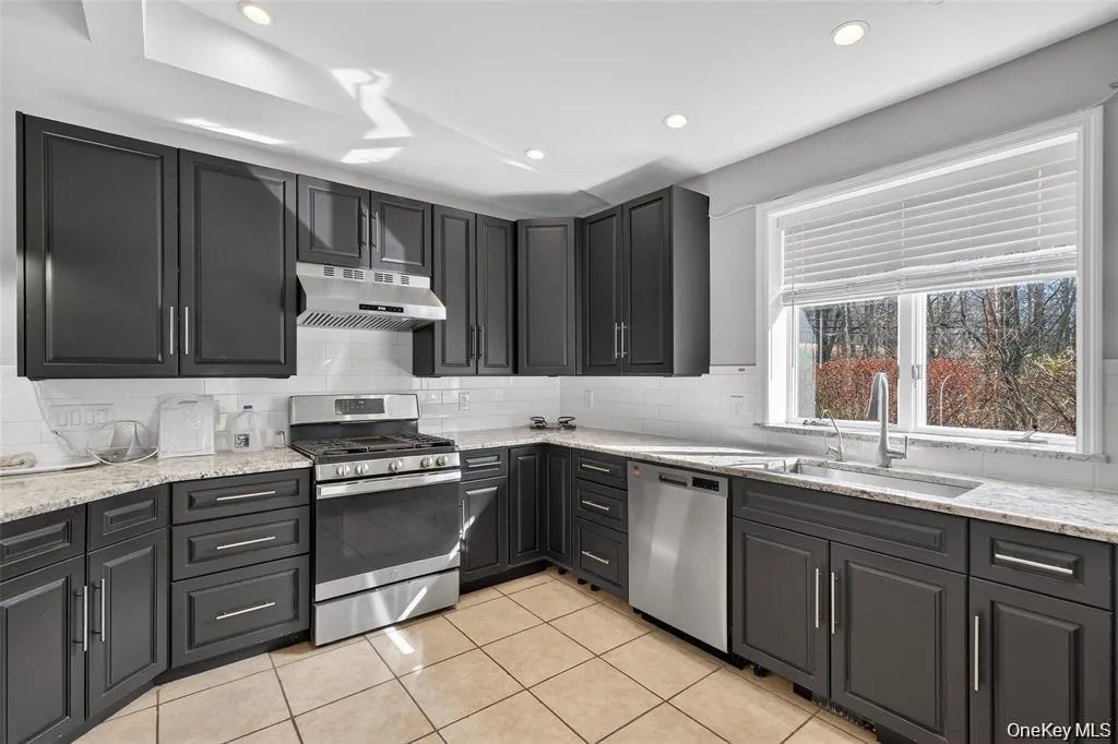 Kitchen with stainless steelappliances, light stonecounters, recessed lighting,light tile patterned floors, andbacksplash Kitchen with stainless steelappliances, light stonecounters, recessed lighting,light tile patterned floors, andbacksplash