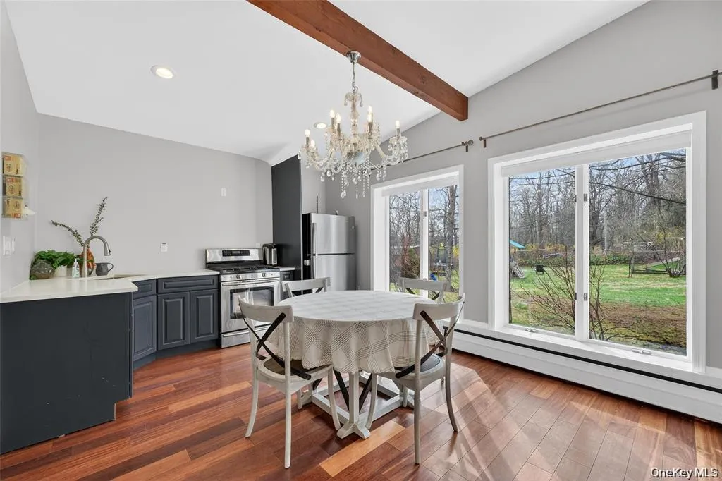 Dining area featuring vaulted ceiling with beams, a chandelier, dark wood-style flooring, and a base board radiator Dining area featuring vaulted ceiling with beams, a chandelier, dark wood-style flooring, and a base board radiator