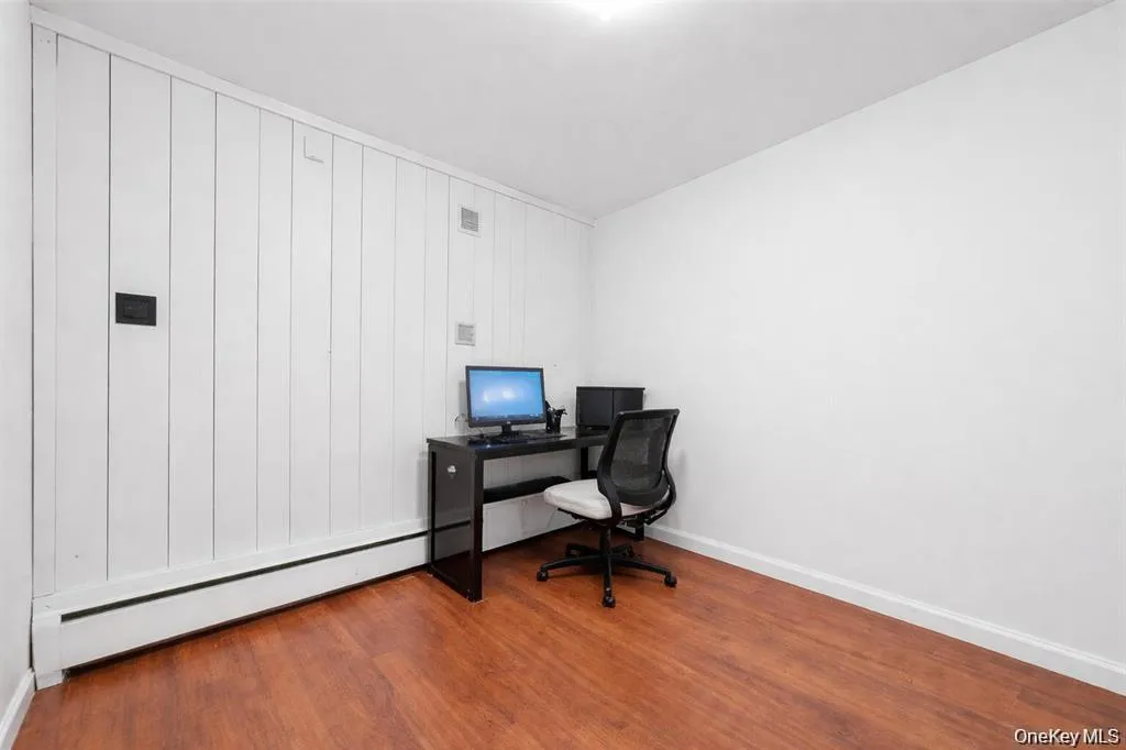 Home office with light wood-type flooring and a base board radiator Home office with light wood-type flooring and a base board radiator