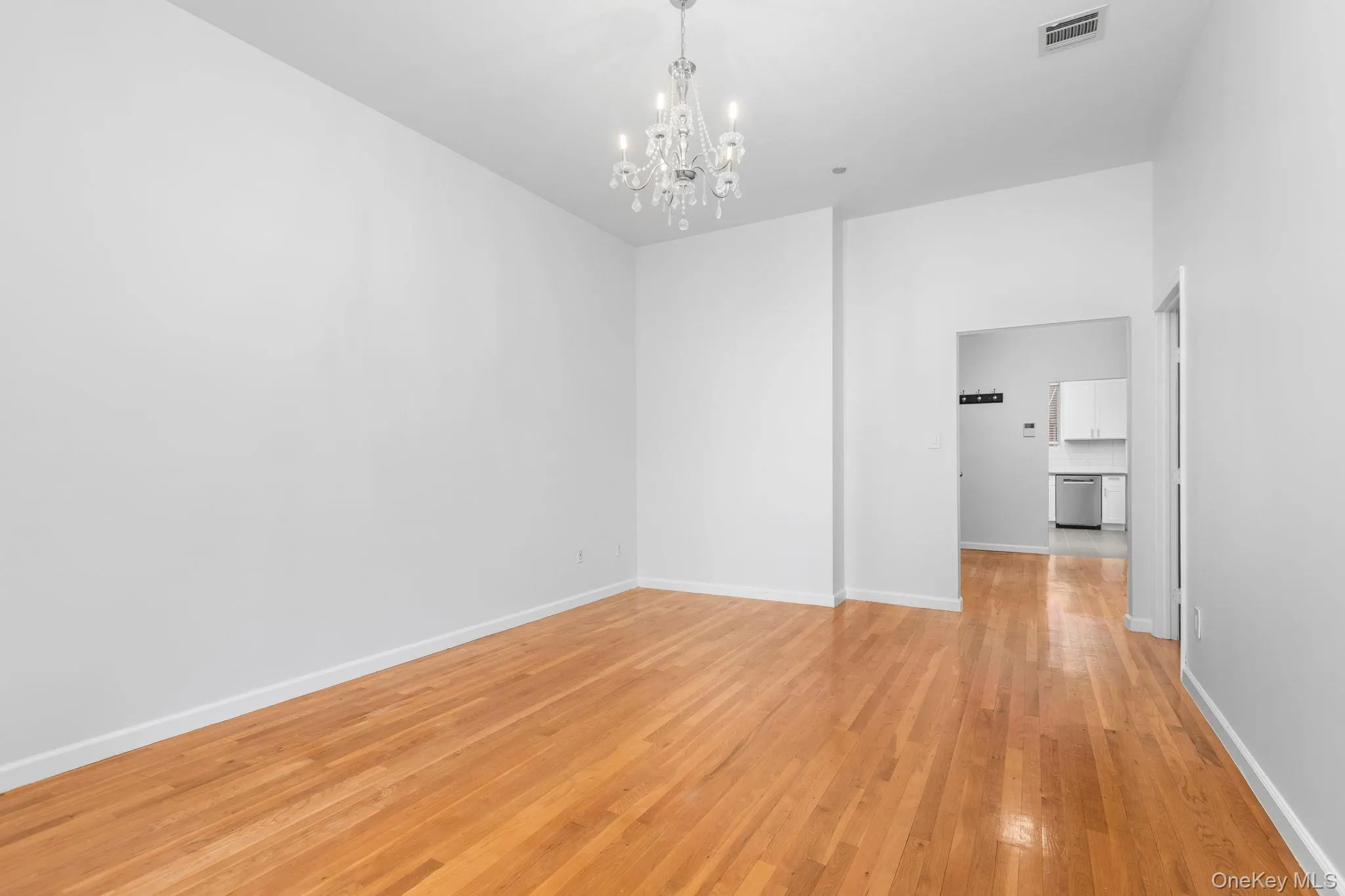 High ceilings featuring a crystal chandelier and light-toned wood-finish flooring High ceilings featuring a crystal chandelier and light-toned wood-finish flooring