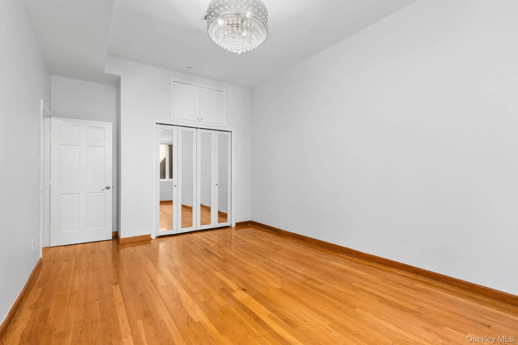 Wood-finish flooring, mirrored closet doors, overhead crystal-style chandelier, and built-in upper storage cabinetry. Wood-finish flooring, mirrored closet doors, overhead crystal-style chandelier, and built-in upper storage cabinetry.