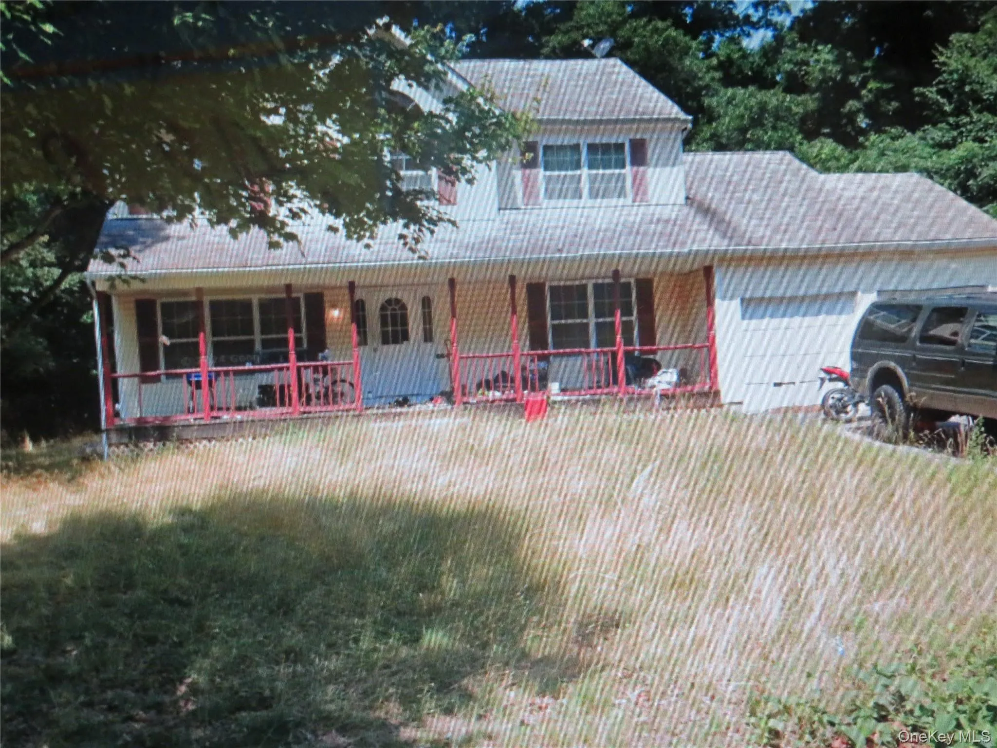 Two-story residence featuring light-colored horizontal siding, a covered front porch, integrated garage, and multi-pane windows with decorative shutters Two-story residence featuring light-colored horizontal siding, a covered front porch, integrated garage, and multi-pane windows with decorative shutters
