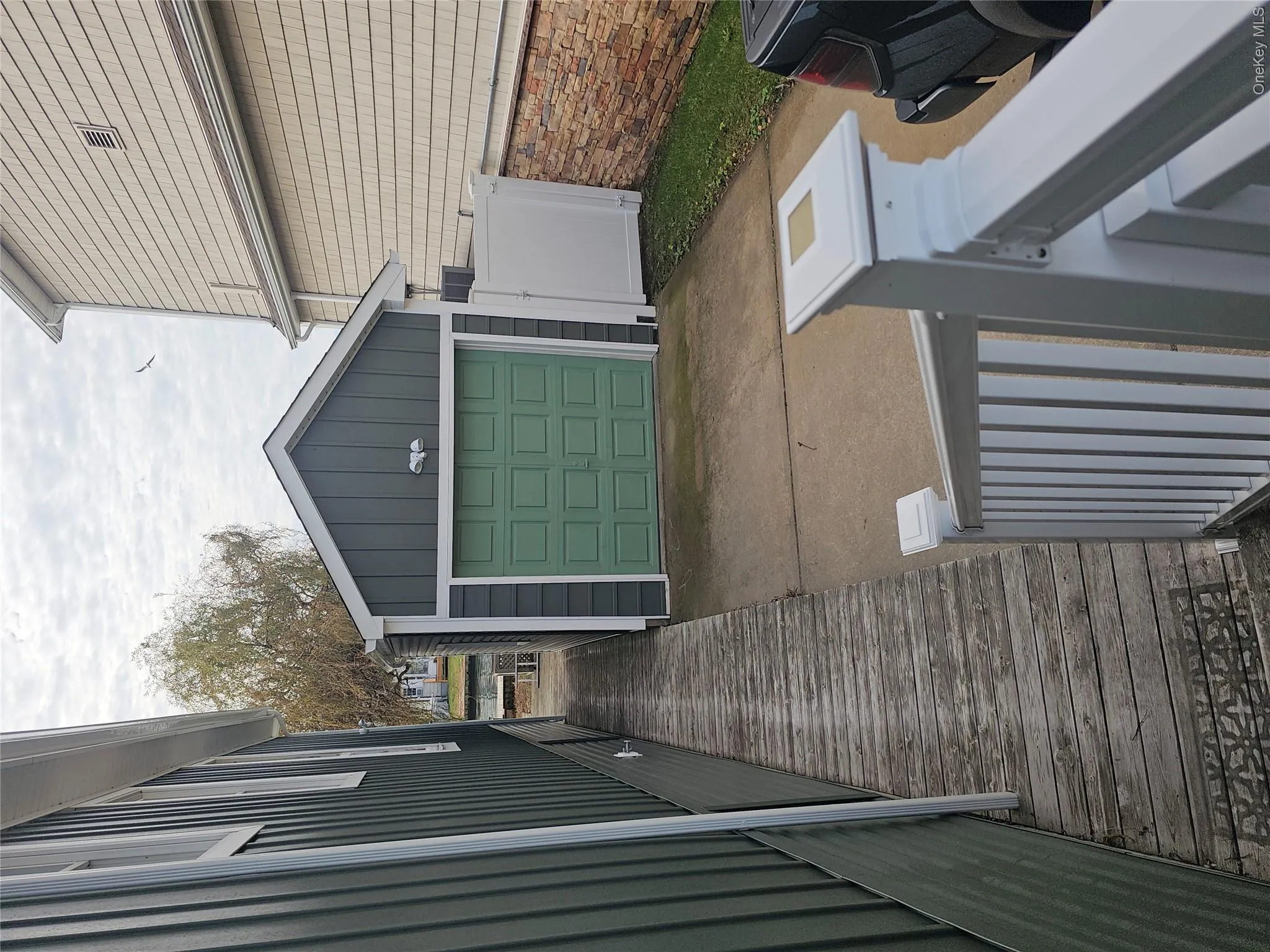 Detached garage featuring vertical siding, concrete driveway, and white vinyl privacy fencing Detached garage featuring vertical siding, concrete driveway, and white vinyl privacy fencing