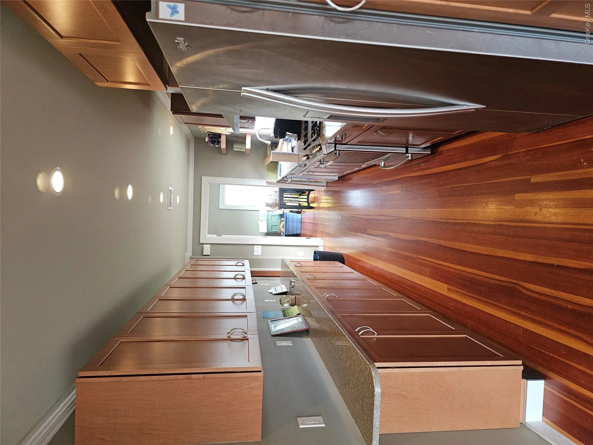 Kitchen featuring extensive wood-finish cabinetry, stone-style countertops, wood-finish flooring, recessed lighting, and stainless steel appliances Kitchen featuring extensive wood-finish cabinetry, stone-style countertops, wood-finish flooring, recessed lighting, and stainless steel appliances