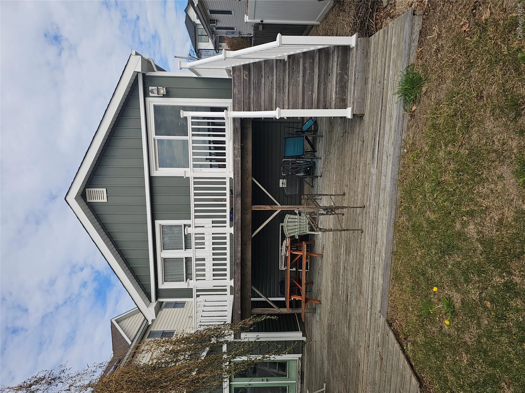 Exterior featuring board and batten siding, elevated deck with white railing, wood-surface patio, and staircase Exterior featuring board and batten siding, elevated deck with white railing, wood-surface patio, and staircase