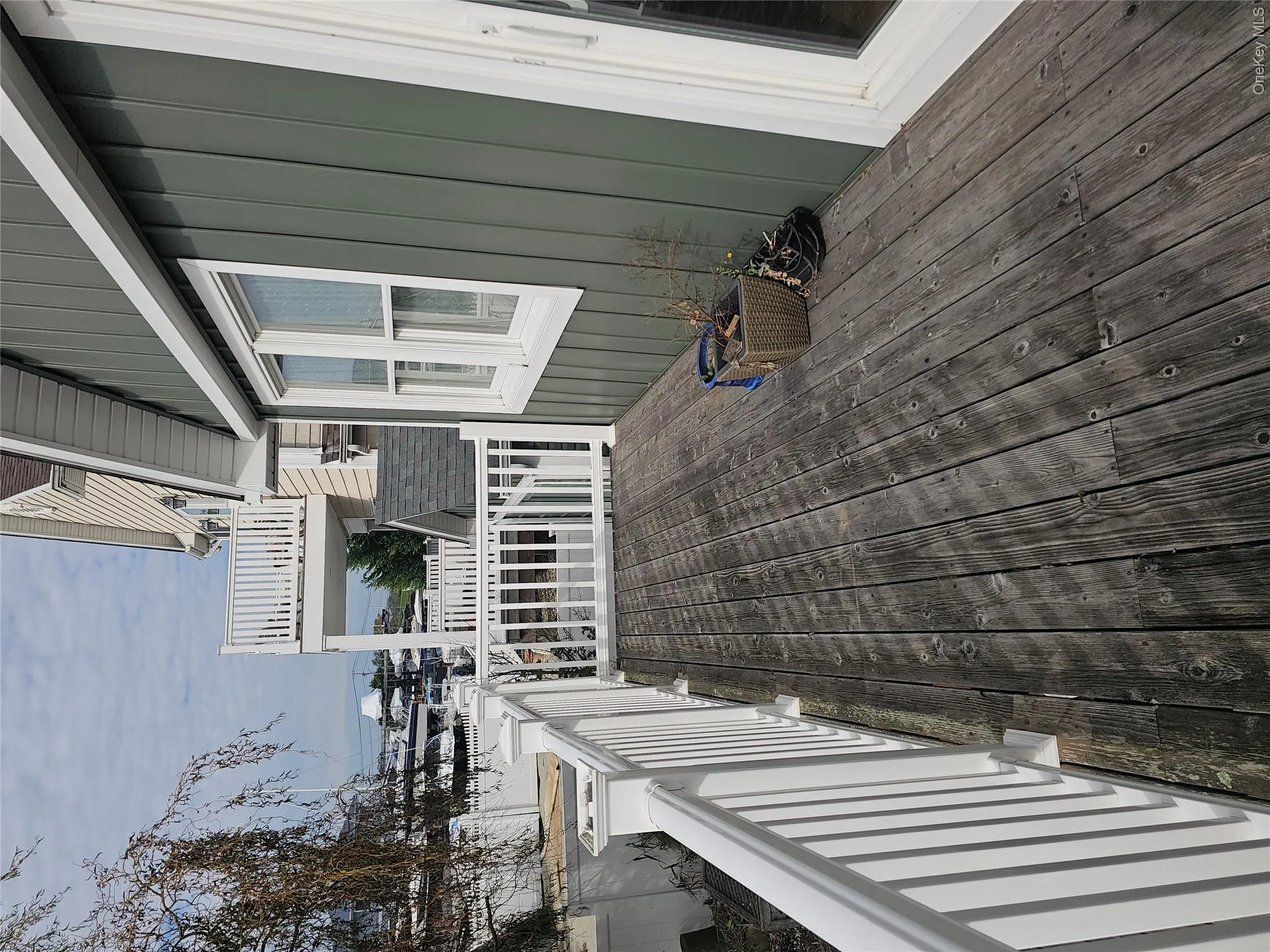 Covered deck featuring vertical siding, white railing, and exterior glass door Covered deck featuring vertical siding, white railing, and exterior glass door