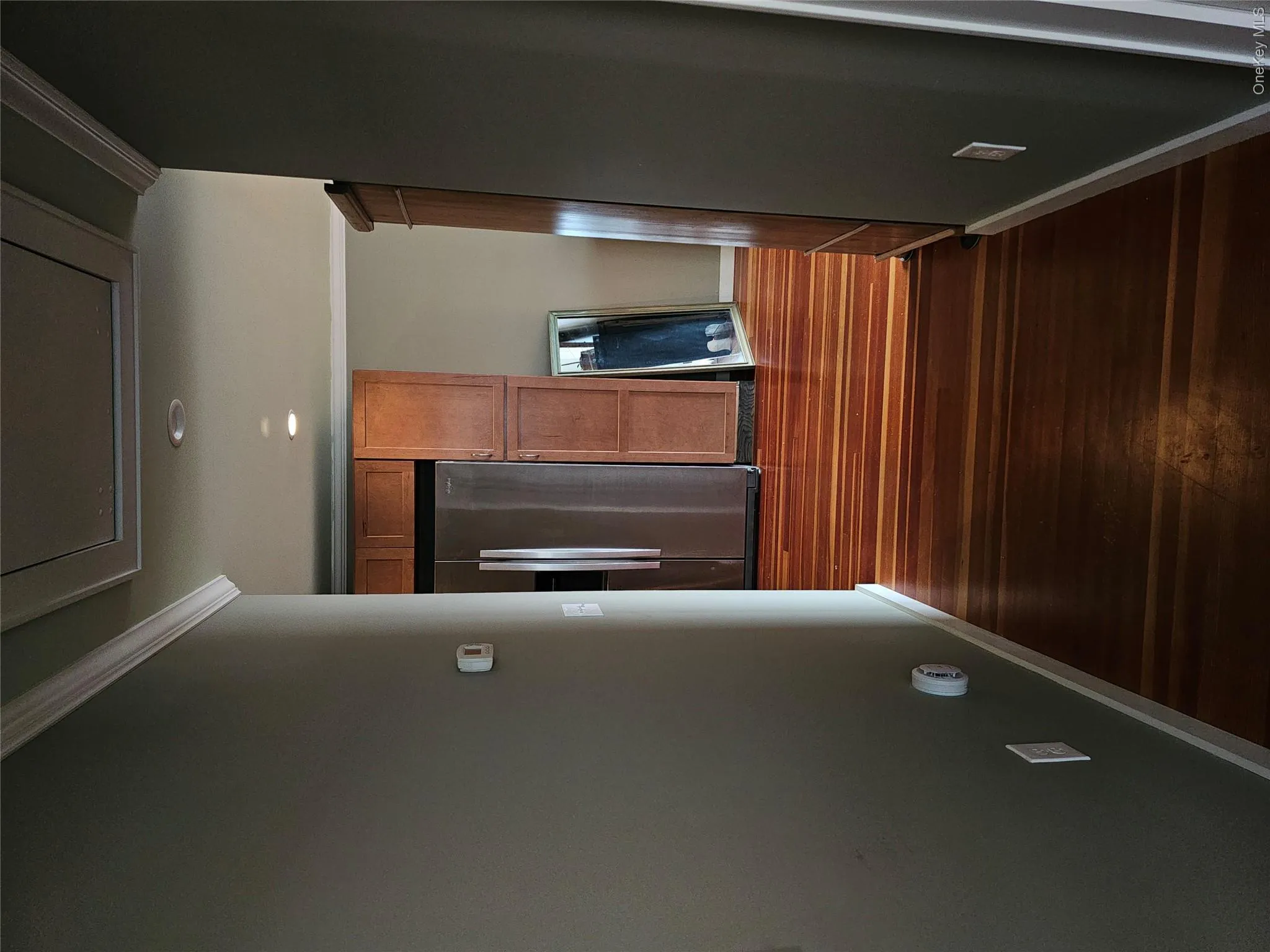 Wood-finish flooring, recessed lighting, crown molding, and wooden cabinetry with a stainless steel refrigerator Wood-finish flooring, recessed lighting, crown molding, and wooden cabinetry with a stainless steel refrigerator