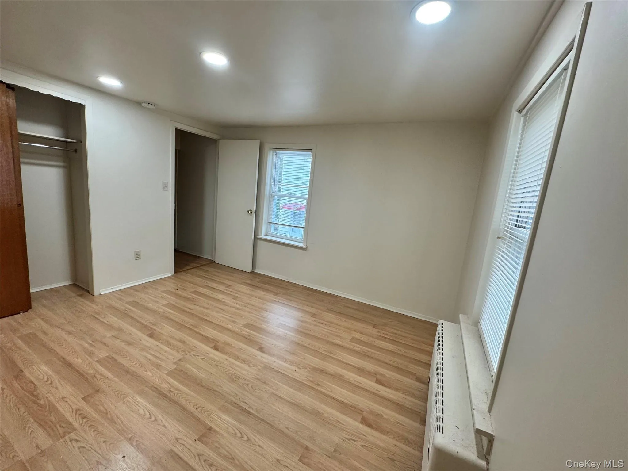 Room featuring wood-finish flooring, recessed lighting, double-hung windows, and a built-in closet Room featuring wood-finish flooring, recessed lighting, double-hung windows, and a built-in closet