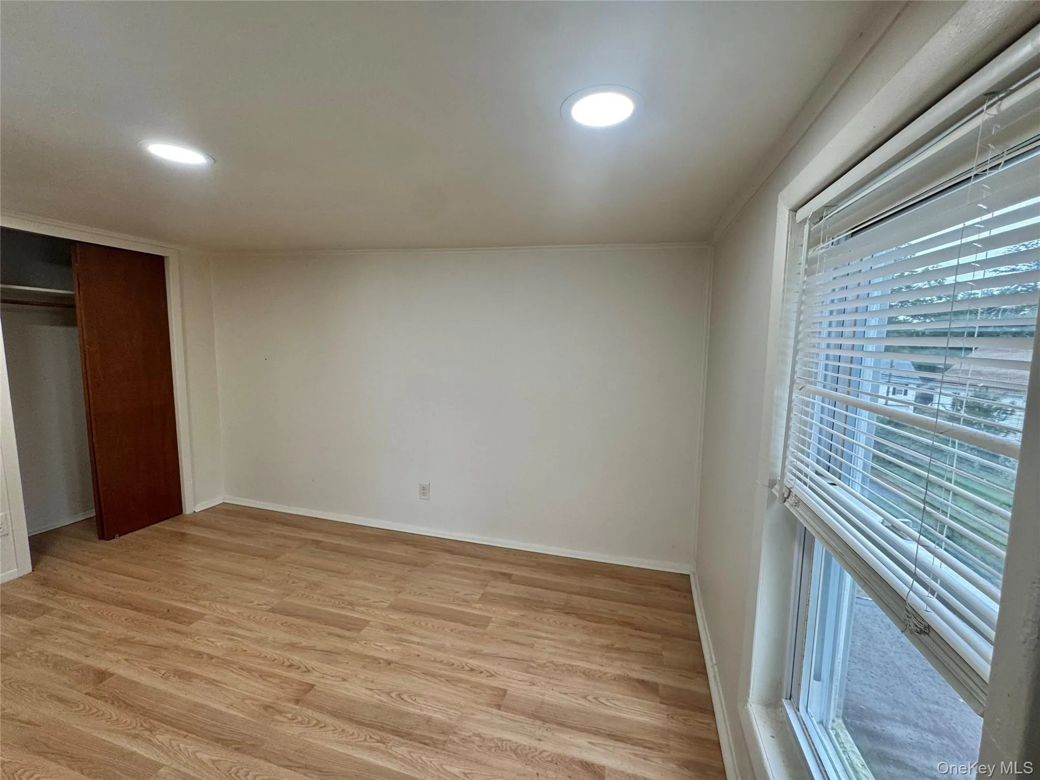 Room featuring wood-finish flooring, recessed lighting, and a sliding-door closet Room featuring wood-finish flooring, recessed lighting, and a sliding-door closet