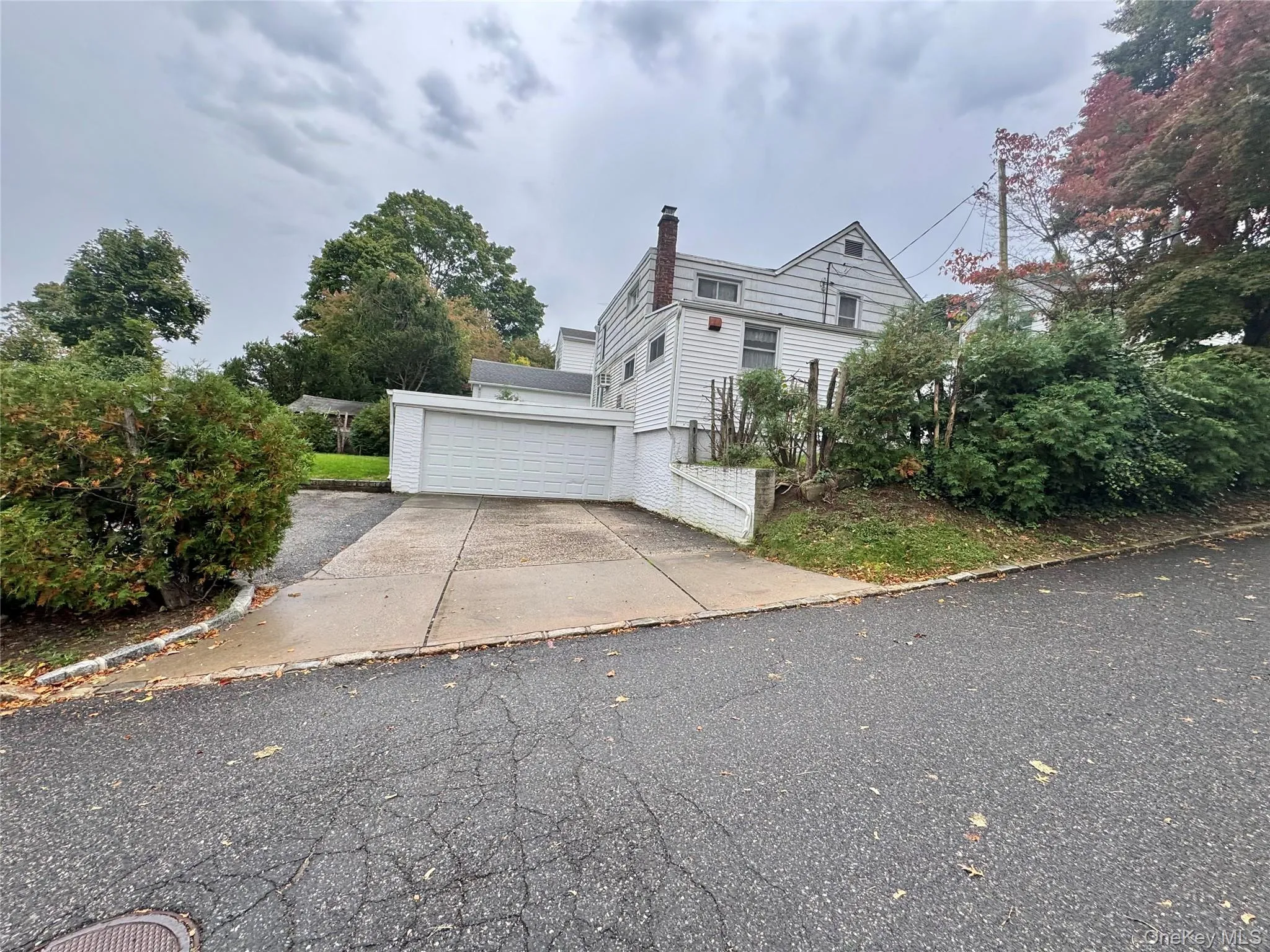 Exterior featuring white horizontal siding, attached two-car garage, concrete driveway, and exterior brick chimney Exterior featuring white horizontal siding, attached two-car garage, concrete driveway, and exterior brick chimney