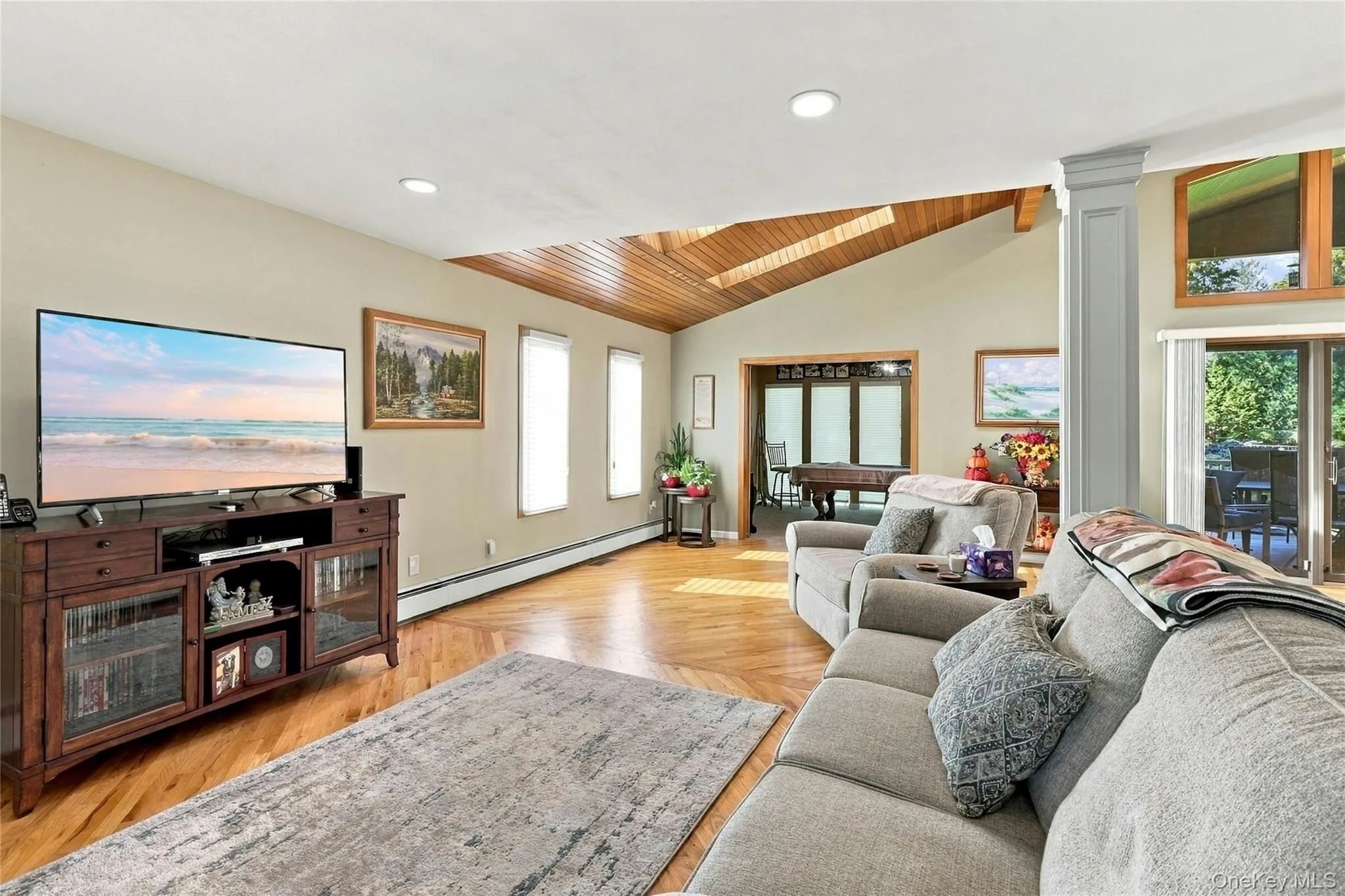 Living area featuring herringbone-patterned wood-finish flooring, vaulted wood-plank ceiling with skylights, recessed lighting, and sliding glass doors Living area featuring herringbone-patterned wood-finish flooring, vaulted wood-plank ceiling with skylights, recessed lighting, and sliding glass doors
