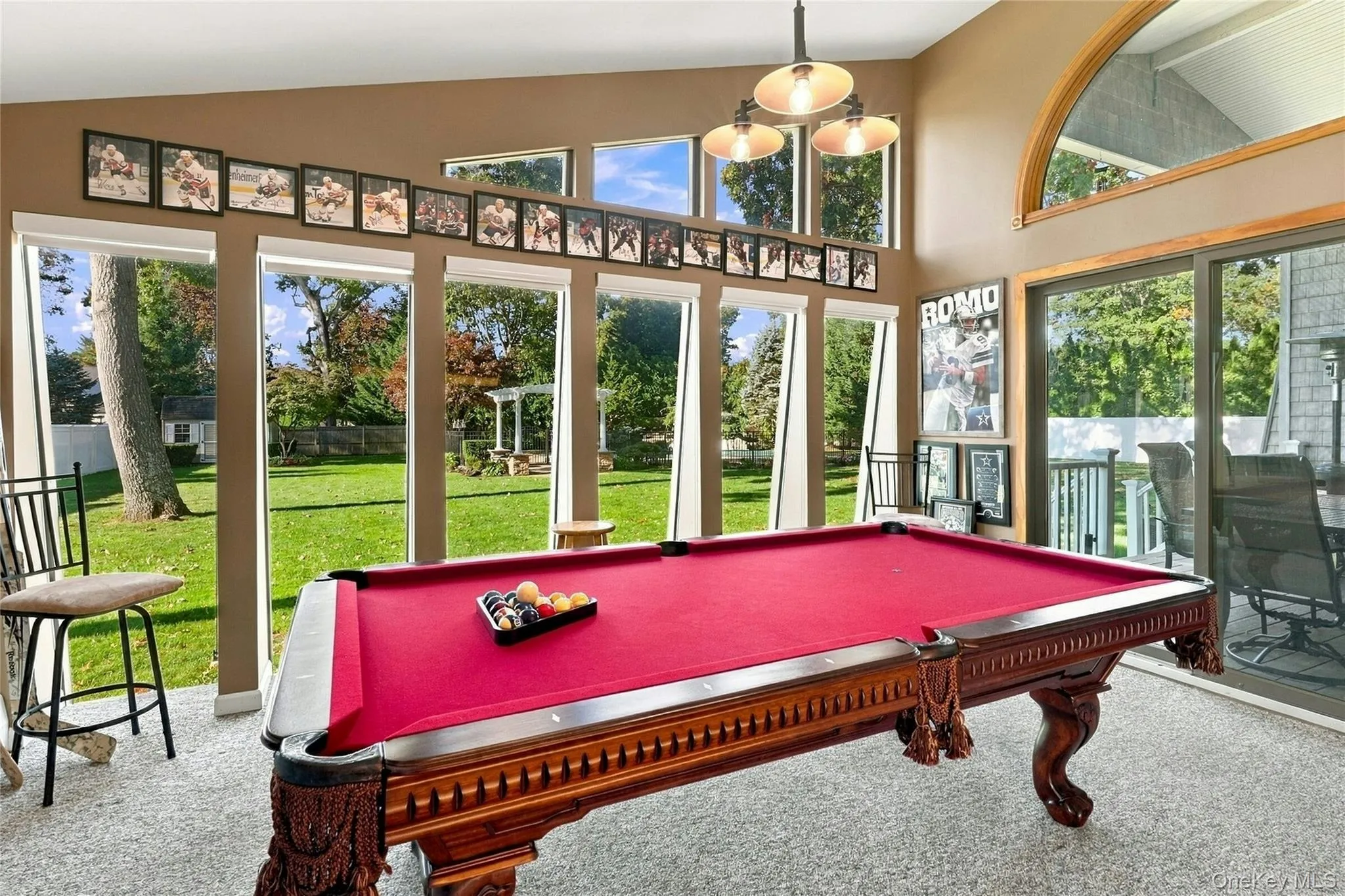 Vaulted ceiling with a multi-light fixture, expansive floor-to-ceiling windows, and sliding glass doors Vaulted ceiling with a multi-light fixture, expansive floor-to-ceiling windows, and sliding glass doors