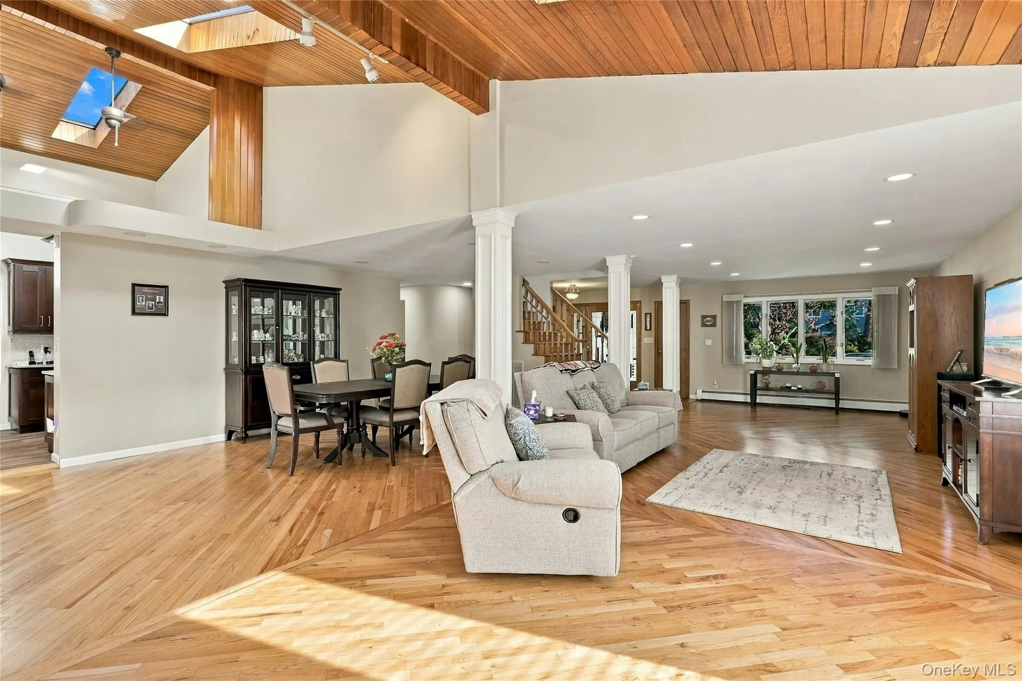 Vaulted wood-plank ceiling, skylights, recessed lighting, structural support columns, and wood-finish flooring Vaulted wood-plank ceiling, skylights, recessed lighting, structural support columns, and wood-finish flooring