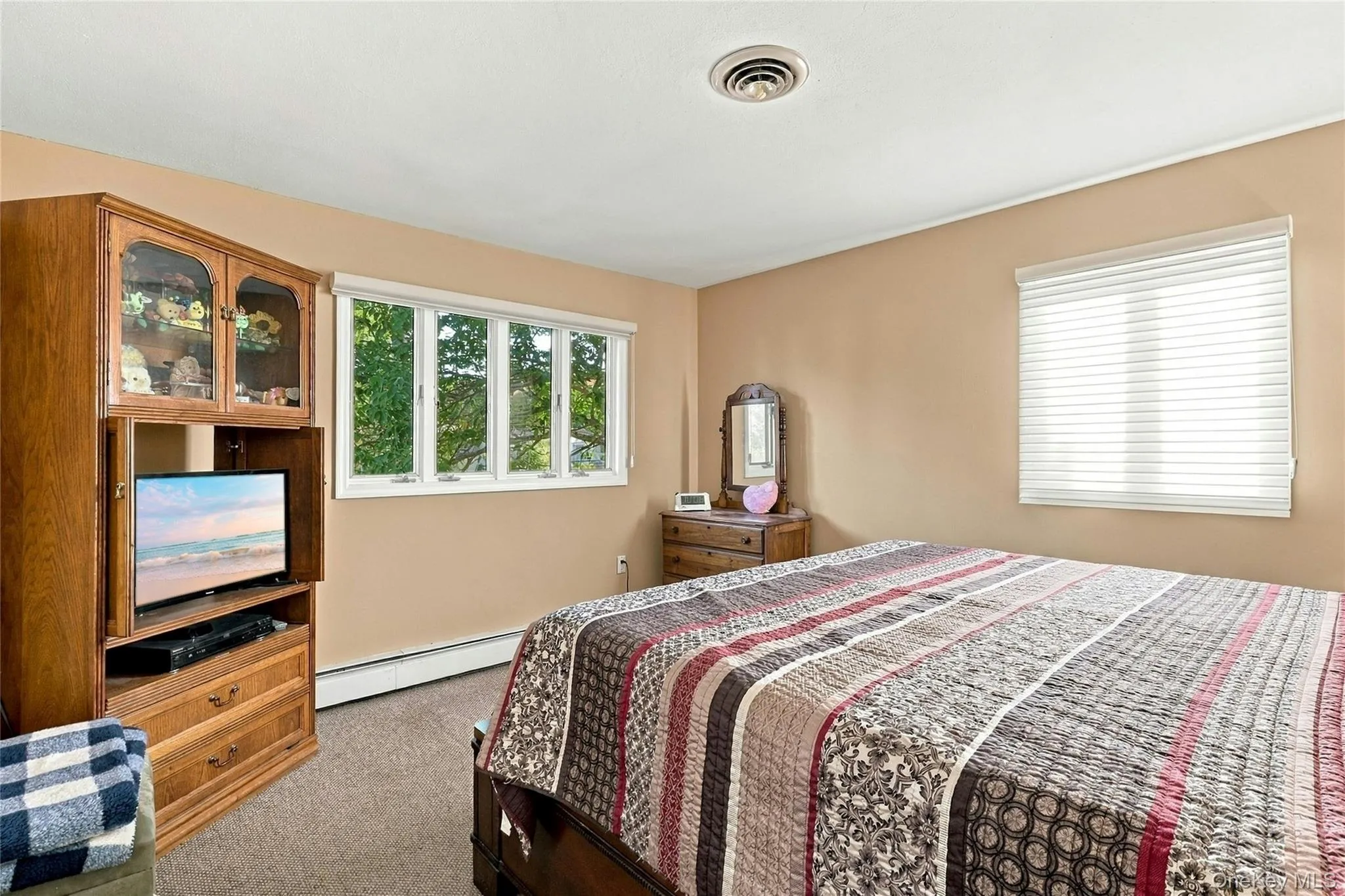 Neutral-toned interior room featuring wall-to-wall carpeting and two windows with white frames Neutral-toned interior room featuring wall-to-wall carpeting and two windows with white frames