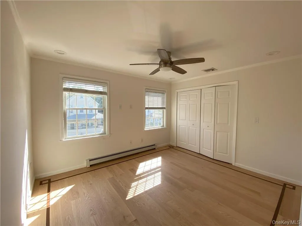 Unfurnished bedroom featuring ceiling fan, light hardwood / wood-style flooring, baseboard heating, and crown molding Unfurnished bedroom featuring ceiling fan, light hardwood / wood-style flooring, baseboard heating, and crown molding