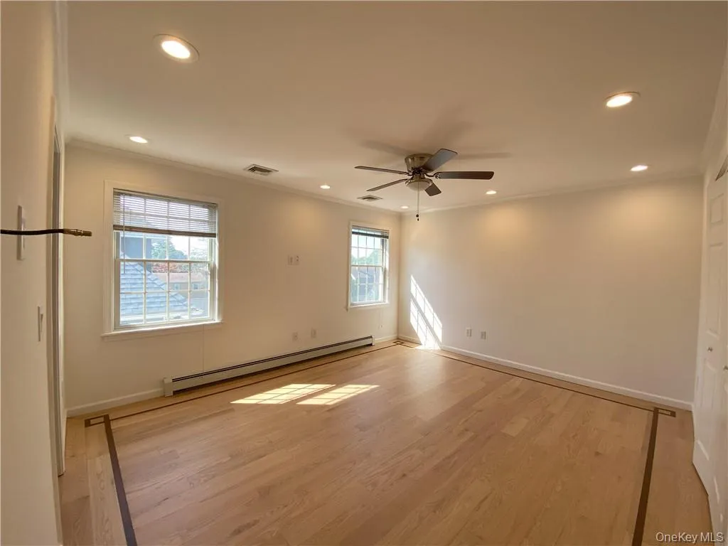 Spare room featuring ceiling fan, baseboard heating, hardwood / wood-style flooring, and ornamental molding Spare room featuring ceiling fan, baseboard heating, hardwood / wood-style flooring, and ornamental molding