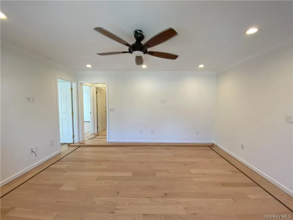 Empty room featuring light wood-type flooring, ceiling fan, and ornamental molding Empty room featuring light wood-type flooring, ceiling fan, and ornamental molding