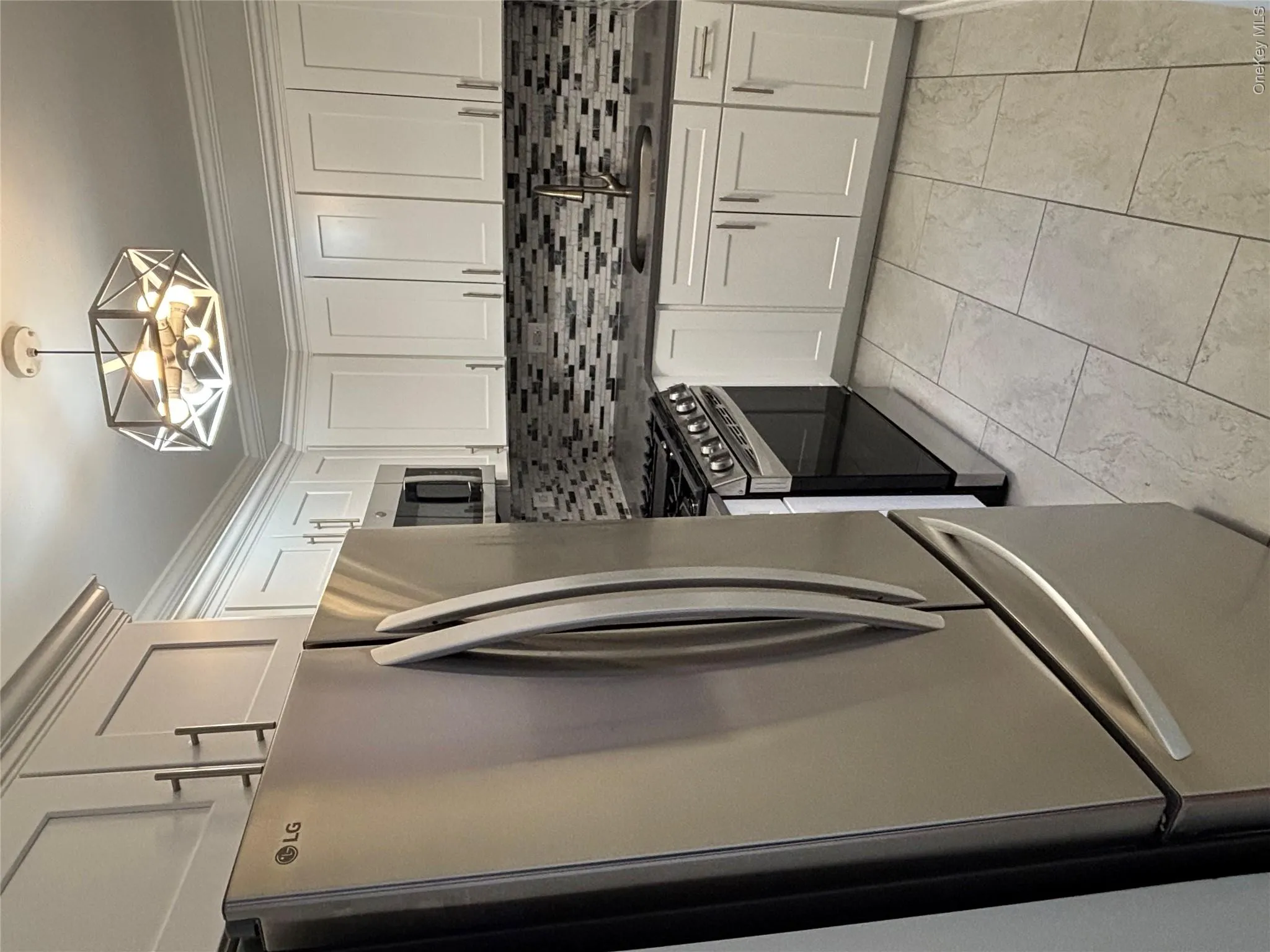 Kitchen featuring stainless steel appliances, tasteful backsplash, white cabinets, and crown molding Kitchen featuring stainless steel appliances, tasteful backsplash, white cabinets, and crown molding