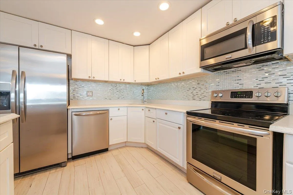 Kitchen featuring appliances with stainless steel finishes, a sink, light countertops, and white cabinetry Kitchen featuring appliances with stainless steel finishes, a sink, light countertops, and white cabinetry