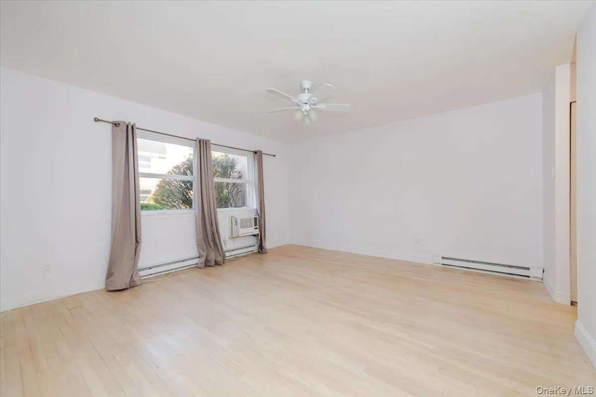 Spare room featuring a ceiling fan, baseboards, light wood-type flooring, and baseboard heating Spare room featuring a ceiling fan, baseboards, light wood-type flooring, and baseboard heating