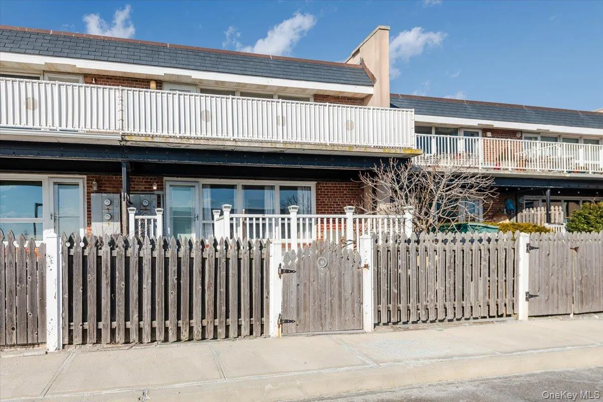 Multi unit property featuring brick siding, a balcony, a gate, and a fenced front yard Multi unit property featuring brick siding, a balcony, a gate, and a fenced front yard