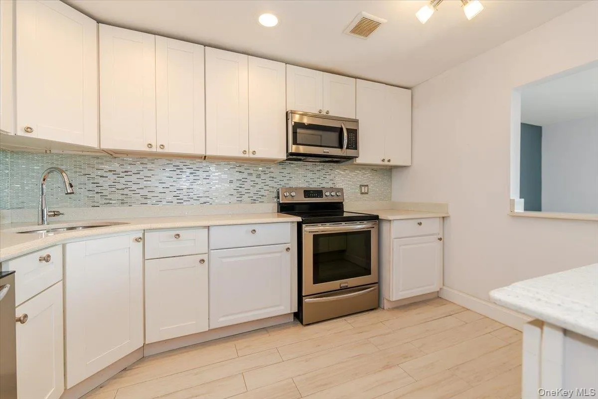 Kitchen with light countertops, white cabinets, visible vents, stainless steel appliances, and a sink Kitchen with light countertops, white cabinets, visible vents, stainless steel appliances, and a sink