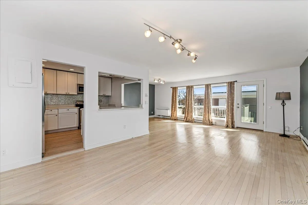 Unfurnished living room featuring light wood finished floors and baseboards Unfurnished living room featuring light wood finished floors and baseboards