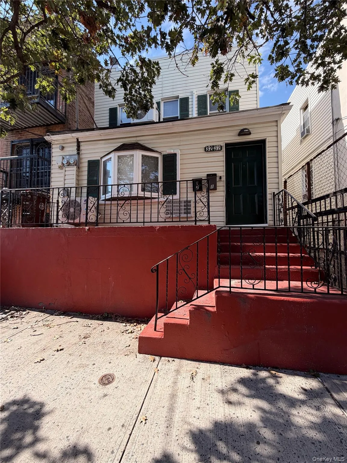 Exterior facade featuring light-colored horizontal siding, a bay window, a covered porch with black metal railings, and a concrete staircase. Exterior facade featuring light-colored horizontal siding, a bay window, a covered porch with black metal railings, and a concrete staircase.