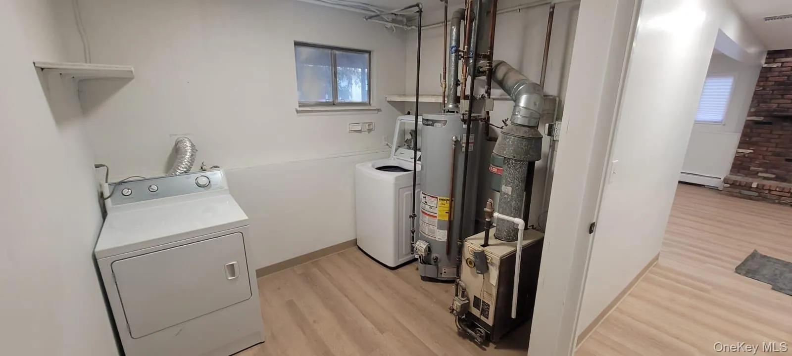 Laundry area featuring washer and clothes dryer, water heater, light wood-type flooring, and a baseboard heating unit Laundry area featuring washer and clothes dryer, water heater, light wood-type flooring, and a baseboard heating unit