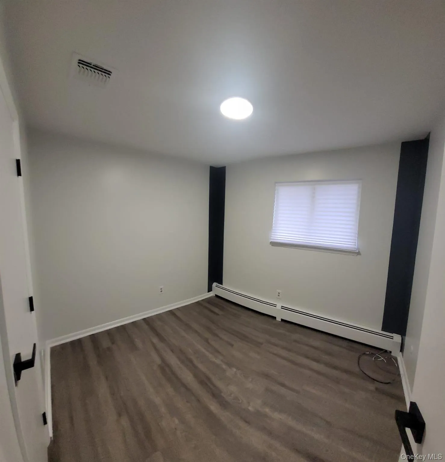 Spare room featuring dark hardwood / wood-style floors and a baseboard heating unit Spare room featuring dark hardwood / wood-style floors and a baseboard heating unit